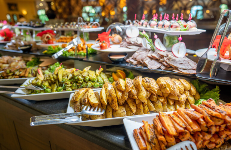 A buffet table with assorted roasted potatoes, grilled vegetables, meats, and appetizers on platters.