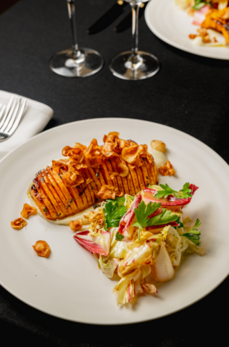 Perfect for climate week catering: Hasselback sweet potato with crispy garlic, paired with fresh mixed salad.